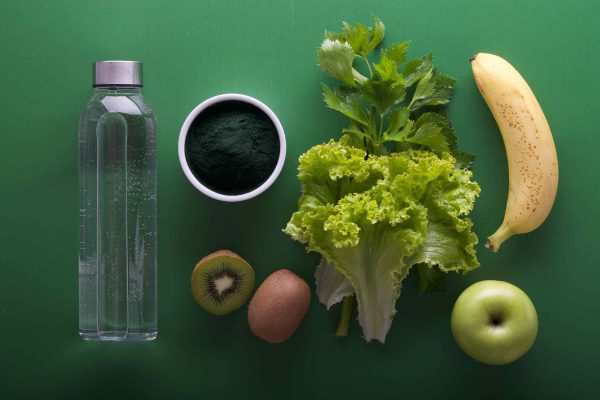 acqua, frutta e verdura su un tavolo verde